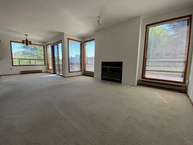 Expansive great room is flooded with natural light and features a classic wood-burning fireplace and large balcony!