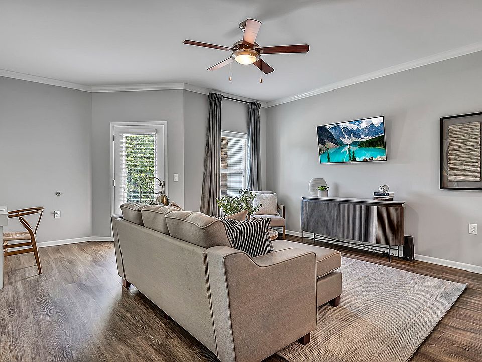 Enjoy the practical peace of a comfortable, grounded living area, with plenty of natural light, wood-style flooring, a ceiling fan, and access to your private patio or balcony.