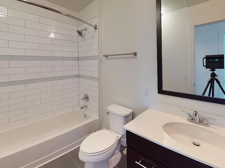 Apartment bathroom with wood-style flooring.