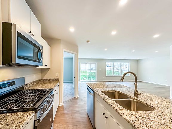 Kitchen - white cabinetry, granite countertops, stainless appliances, double-basin sink in center is