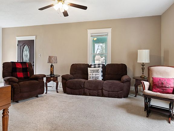 The large sunny living room has hardwood floors under the carpet and a lovely vintage staircase.