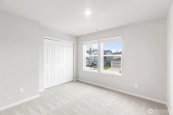 2nd bedroom with large windows and front yard views