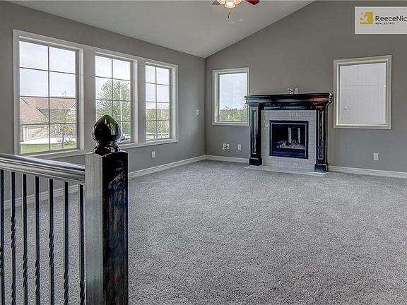 Custom tiled gas fireplace with stained mantel, large windows and ceiling fan in great room. Square metal stair spindles in choice of black or oil rubbed bronze.