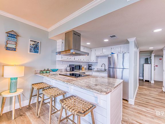 Kitchen with a breakfast bar, light wood-type flooring, backsplash, exhaust hood, and stainless steel appliances