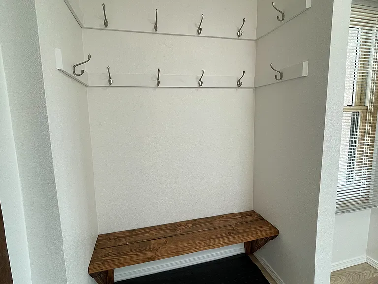 Mud room with bench and two rows of hooks for coats, hats, and bags.