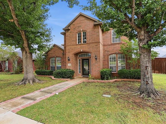Brick facade residence featuring a front entry with an arched transom, multiple arched windows, and a brick-lined walkway