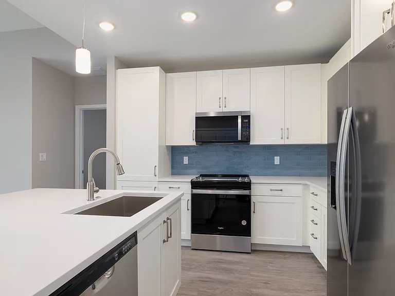 Imperial Crossing Luxury Apartment Homes unit showing a modern kitchen with stainless steel appliances and white cabinets.