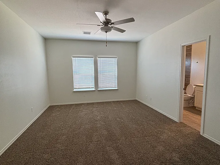 Bright and spacious primary bedroom with ceiling fan and attached private bath.
