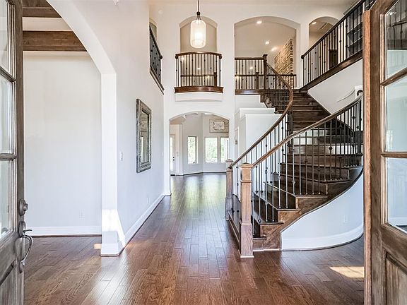 2 story entry way with wood floors and curved staircase.