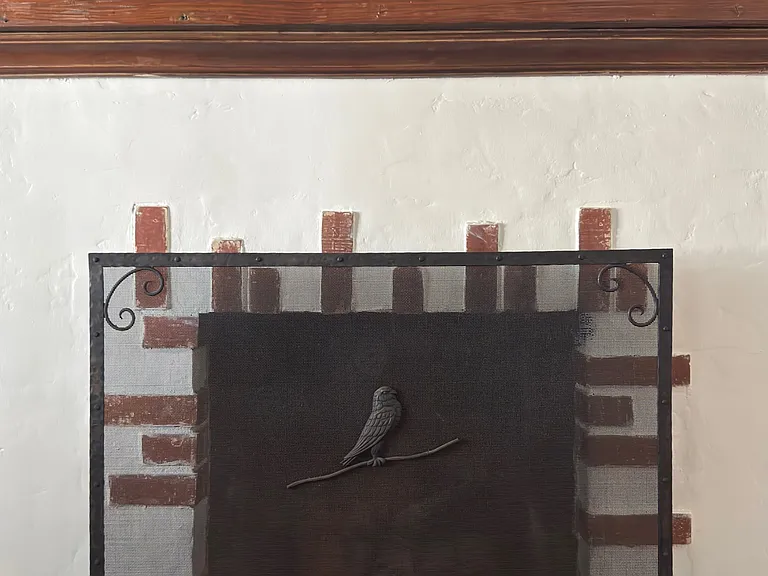 Fireplace detail - original brick fireplace with wrought-iron screen.
