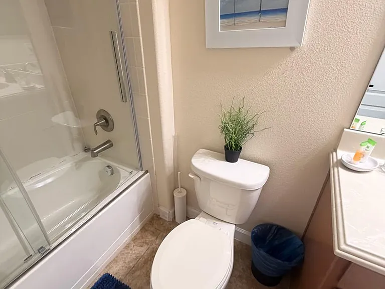 Full bathroom with tub/shower combo, sliding glass doors, and a vanity for everyday storage and prep space.