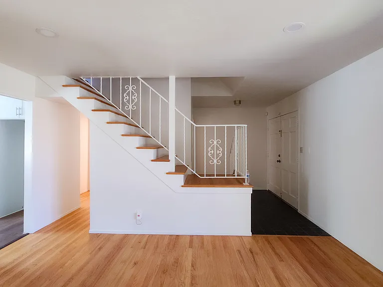 Open living area with staircase access to the second floor and updated wood- style flooring