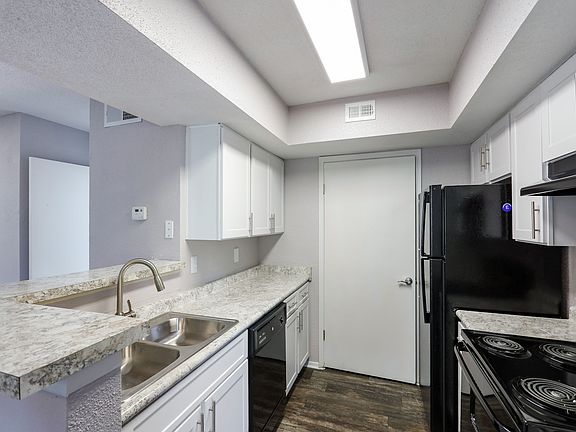 Model Kitchen with custom cabinets, wood style flooring, and black appliances.