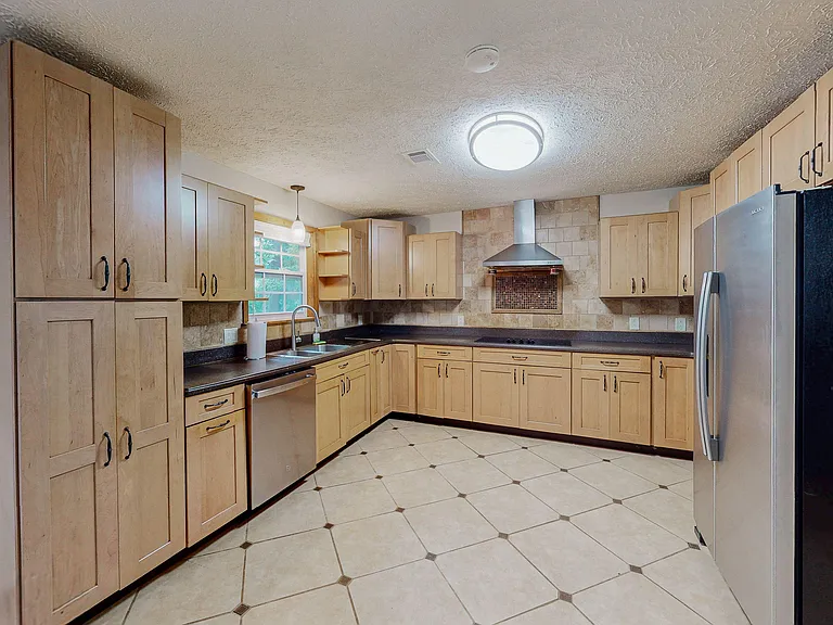 Spacious U-shaped kitchen with ample cabinet storage, tile backsplash, stainless appliances, and a large prep counter.