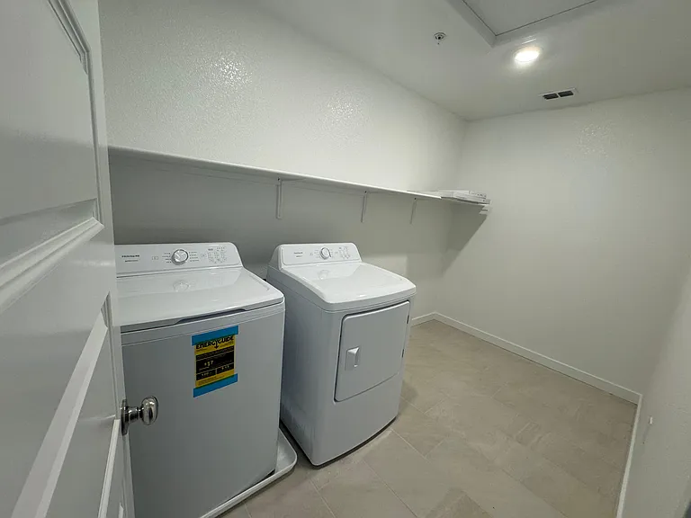 Spacious laundry room with brand new washer and dryer and extra storage space.