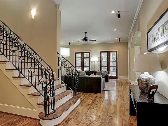 The beautiful hardwoods continue through the hallway into the family great room and stairway with detailed wrought iron banister.