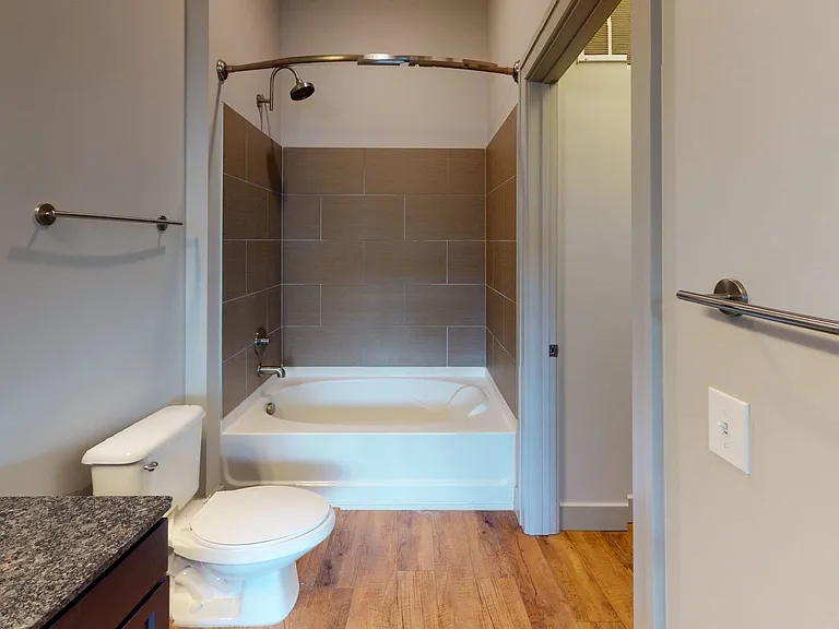 Apartment bathroom with large soaking tub and wood-style flooring.