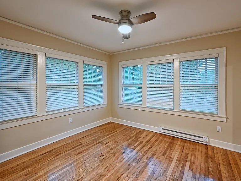 View into bedroom from bathroom hallway. Bedroom has baseboard heater for extra heat