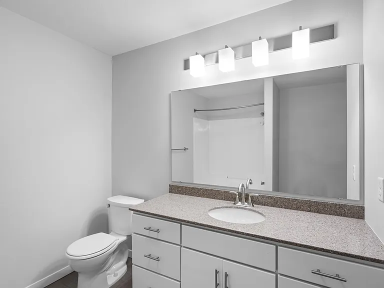 Modern bathroom with sleek vanity, polished granite countertop, elegant lighting, and a pristine bathtub. Modern bathroom with sleek vanity, polished granite countertop, elegant lighting, and a pristine bathtub.
