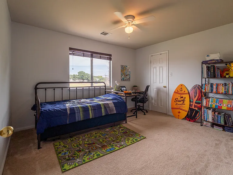 Comfortable Secondary Bedroom: A bright and spacious bedroom complete with plush carpeting, a large window offering open views, and a ceiling fan. This versatile room easily accommodates a bed, workspace, and storage layout.