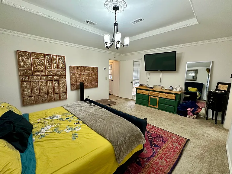 Primary bedroom featuring a notable chandelier, carpet, a tray ceiling