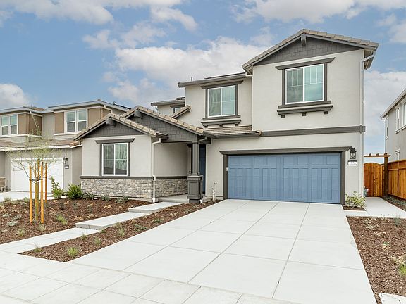A modern two-story residential house with a garage, surrounded by a landscaped yard and a clear blue