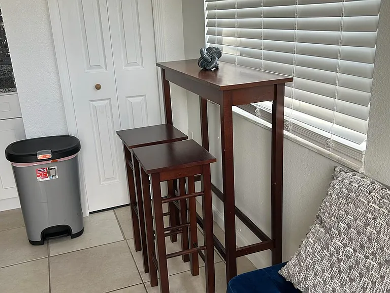 Dining area with table for two and trash bin for added convenience.