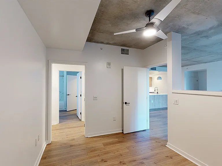 Spacious apartment bedroom with attached bathroom and wood-style flooring.