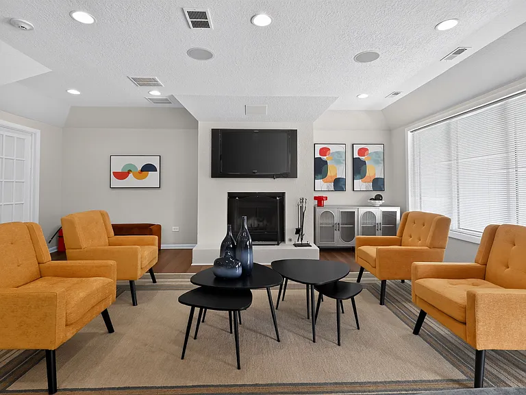 Relax and unwind in the community clubhouse featuring a cozy fireplace and TV at Renaissance at Carol Stream in Carol Stream, IL.