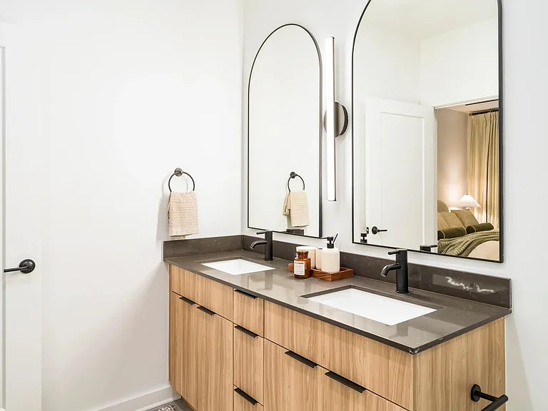 This refined primary bath finish option at Modera Nations in Nashville features sleek double vanities, modern fixtures, and a clean, timeless design.
