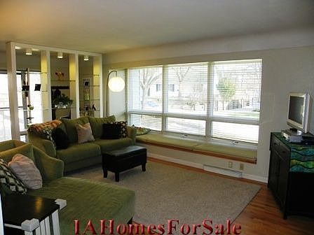Living Room with beautiful hardwood floors, coved ceiling, window seat with storage underneath, decorative shelves with lighting and large windows.