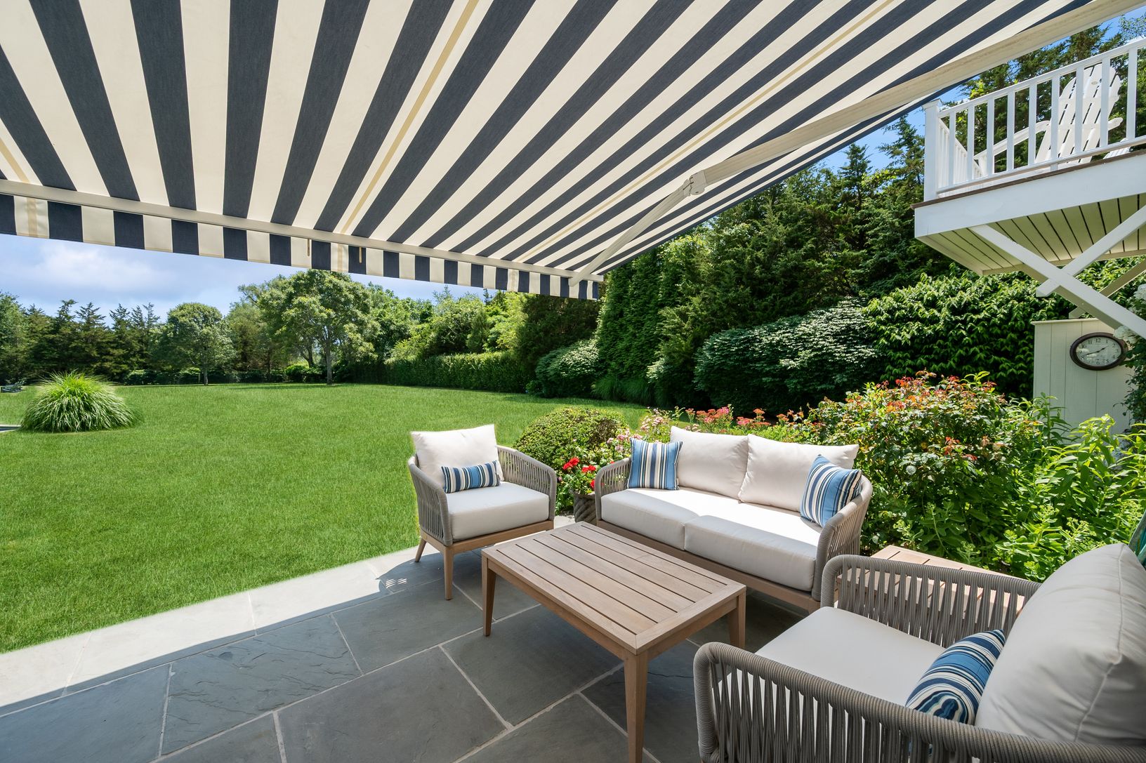 Southwest view from Sunroom patio with far right outdoor shower, awning, and apt balcony and garden