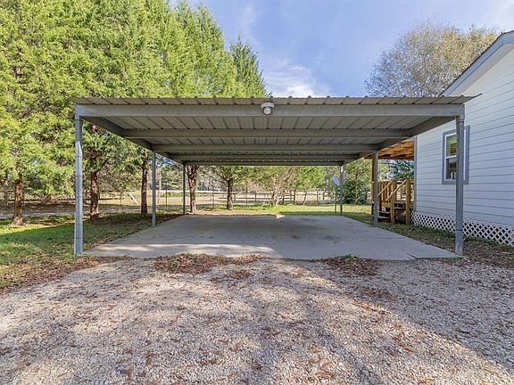 Covered parking with a concrete slab and access to back patio.
