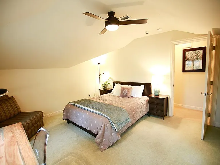 Upstairs bedroom #1 with a queen-sized bed and padded headboard. Note that due to the camera lens the ceiling appears to be lower than it actually is and the unique curves in the ceiling add an interesting dimension to the space.