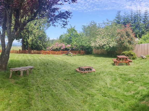 Backyard from Breezeway, picnic table, fire pit, and cattle pasture just beyond the back fence.