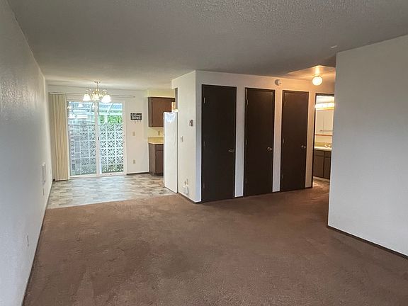 in living room, looking toward dining room. the bathroom is lit up in the right back corner. three closets in the hall