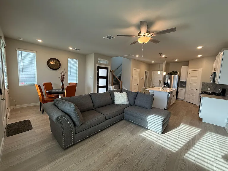Open-concept living area with ample seating, adjacent dining nook, and a kitchen with an island and pendant lighting.