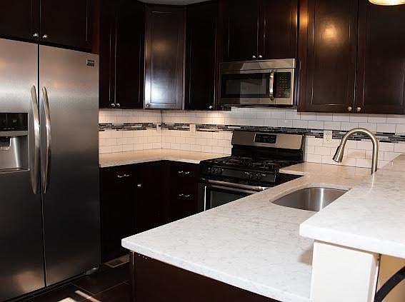 Updated kitchen with marble counters, dishwasher, gas stove, garbage disposal, and stainless appliances
