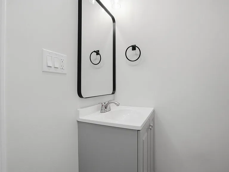 Clean vanity area with a single-sink cabinet, framed mirror, and wall-mounted towel ring for everyday convenience.