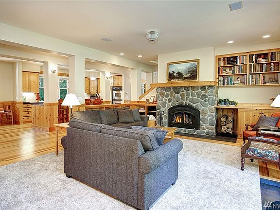 Pine wood floors recently refinished are throughout the great room!  Notice the stone fireplace, the built-in bookshelves that are both to the right of the fireplace and behind the couch at the half-wall between the living room and kitchen.  Super cool!