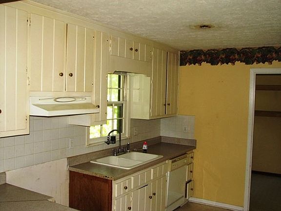 Kitchen has painted wood cabinets, laminate counters and tile backsplash. (It needs a stove and a re