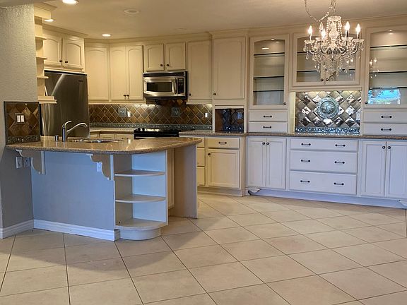 From the main living room, you have direct, step up access to the custom kitchen and dining room, featuring beautiful cabinetry, counters, backplash, and lots of storage