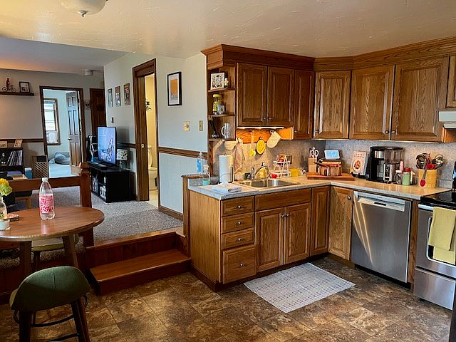Kitchen and Living room area. Stainless steel dishwasher, stove and refrigerator.