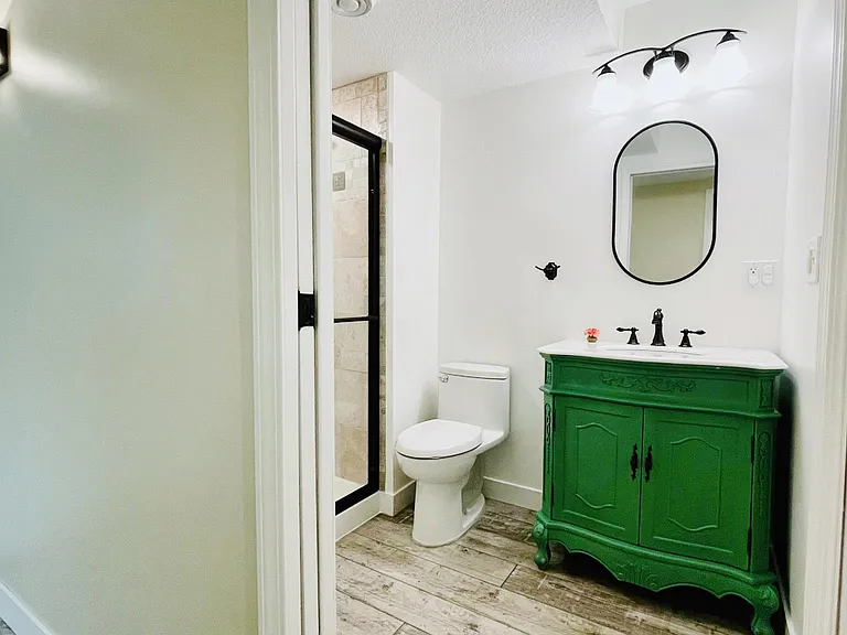Basement Bathroom. Recently Updated. Brand new Vanity/Mirror/Toilet/Flooring/Wall. The right hand side panel door opens to large storage space under the stairs. Vanity color is now showing correctly in this picture, it is in light green that is very close