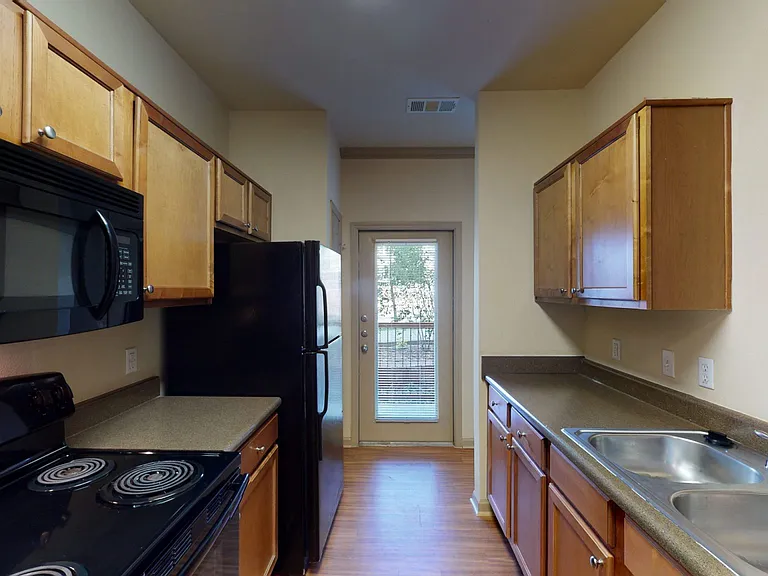 Apartment kitchen with wood-style flooring.