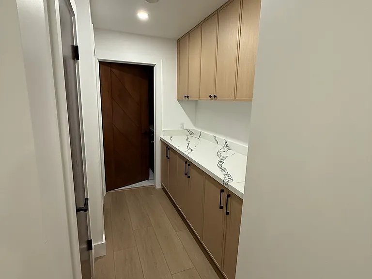 Hallway to 2nd bedroom and bathroom; additional storage cabinets and counter