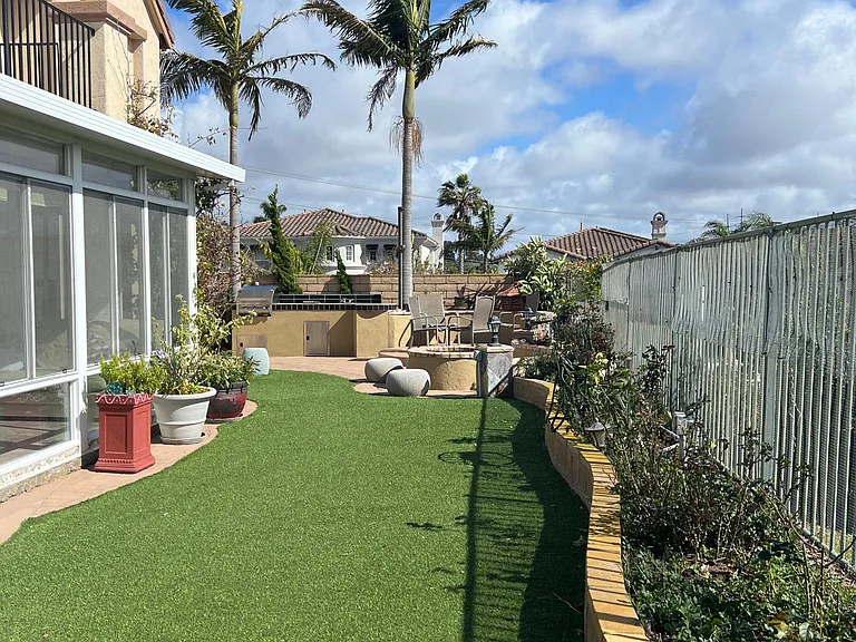 Backyard with artificial turf/grass. View of the sunroom from outside.
