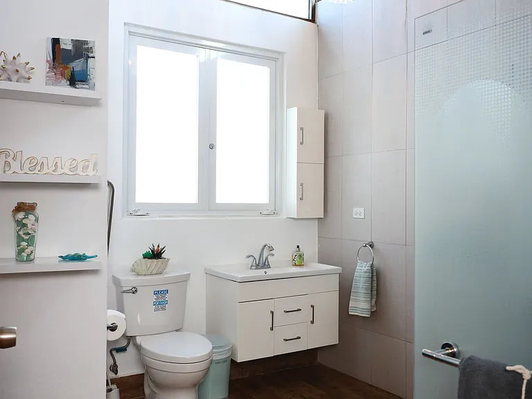 Big confortable bathroom with shower and high ceiling with lots of natural light