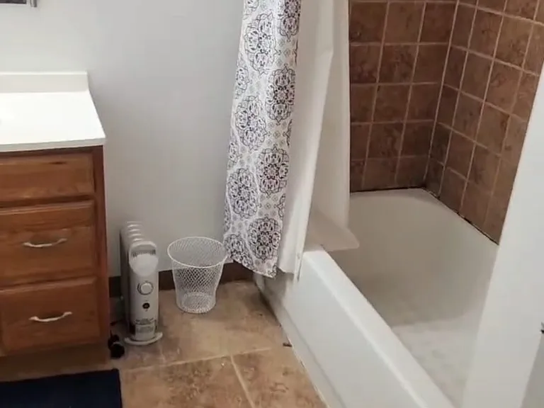 photo shows the shower bathtub and vanity sink in the shared full-size bathroom which also includes a brand new power flush toilet and a laundry closet with a full size dryer and a medium-sized washing machine with electronic start button