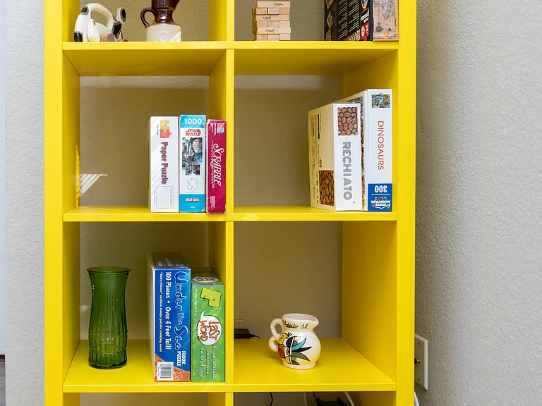 Cozy, spacious living room featuring a comfy couch, two chairs, a warm fireplace, TV, and a bookshelf stocked with books and games_perfect for relaxing or entertaining.